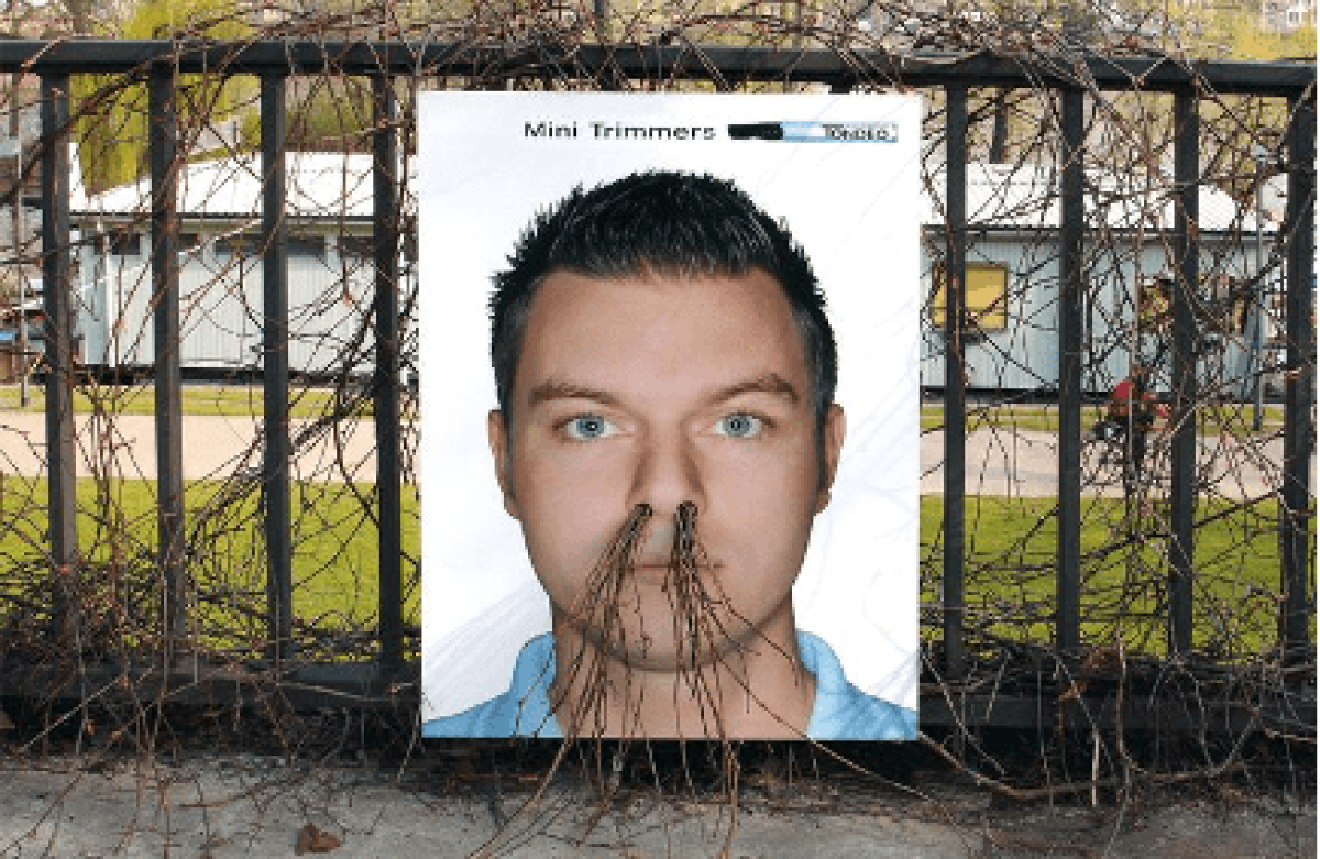Poutač na plotě - muž, kterému nosními dírkami prorůstá keř