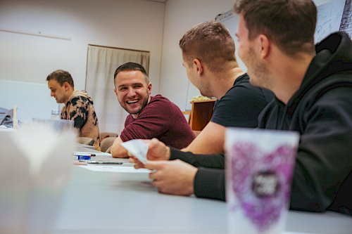 Tým sedící u stolu v zasedačce, uprostřed CEO, který se směje